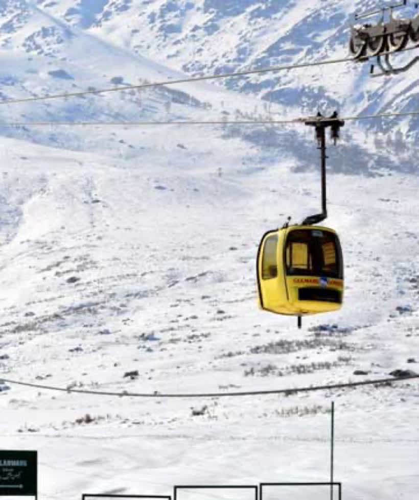 The yellow Gulmarg gondola rising over snow-covered slopes